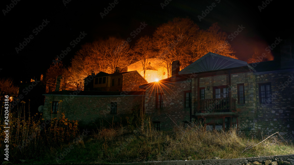 night photo of a traditional house and an orthodox christian church in the village of Nymfaio in Macedonia in Greece