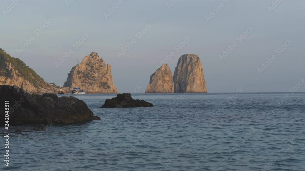 Anchored sail boat agains Faraglioni sea stack at sunset. Capri, Italy Anchored sail boat agains Faraglioni sea stack at sunset. Capri, Italy