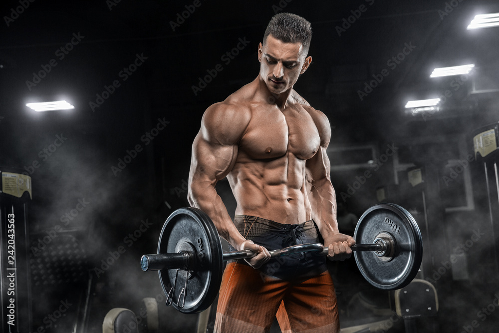 Young handsome sexy man, athlete, bodybuilder, weightlifter, in a modern  gym is covered with a dark background, doing exercises for the biceps using  sporting goods - weights. Stock Photo | Adobe Stock