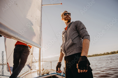 Successful young bearded man sailing portrait at sunrise on boat