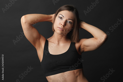 horizontal Studio half-length portrait of a beautiful girl in excellent physical shape, sportswear, uniform dark background