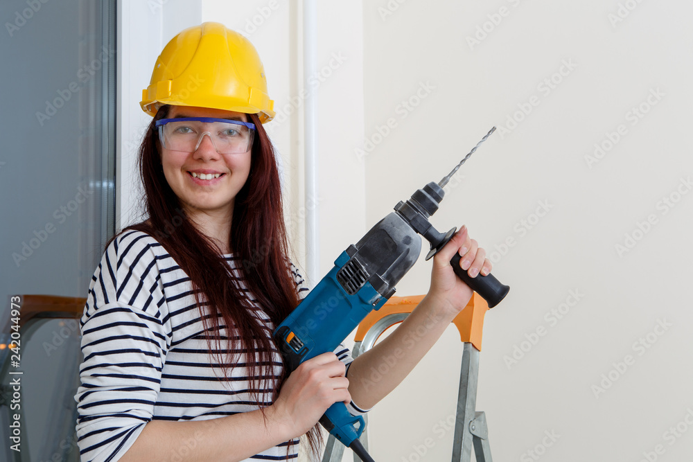 Photo of woman in helmet with drill in hand at window Photo of woman in helmet with drill in hand at window