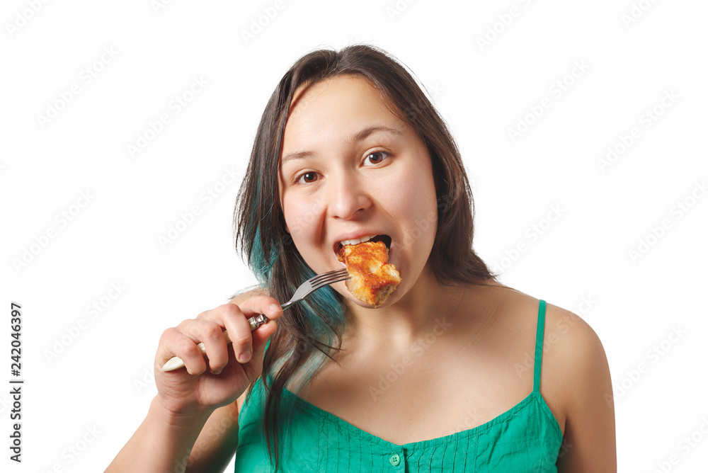 the girl looks in the frame and eats a piece of fried meat on a fork. isolated on white background the girl looks in the frame and eats a piece of fried meat on a fork. isolated on white background