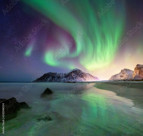 Aurora borealis on the Lofoten islands, Norway. Green northern lights above mountains and beach. Night sky with polar lights. Night winter landscape with aurora.