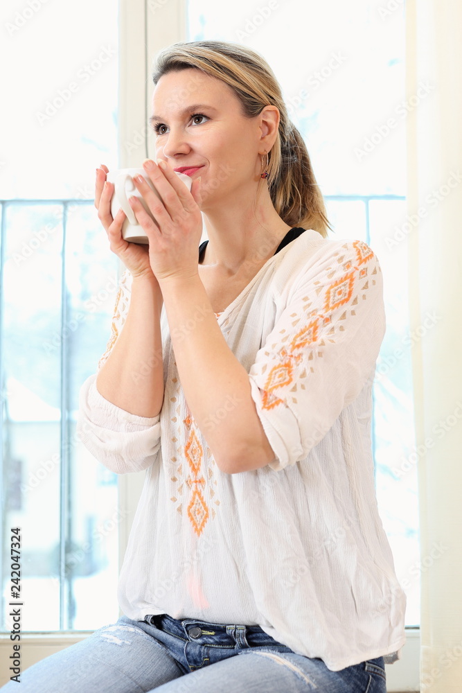 Frau achtsam entspannt mit Kaffe Tee Tasse vor Fenster Frau achtsam entspannt mit Kaffe Tee Tasse vor Fenster