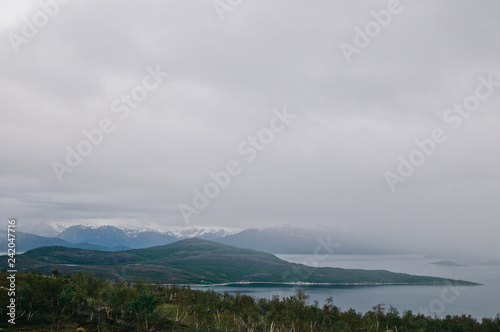 Scenic view in Northern Norway. Fjord and snow mountains in the fog