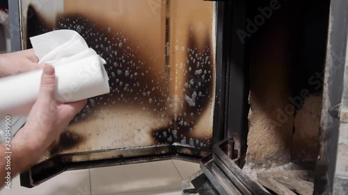 A man cleans glass by a fireplace from soot