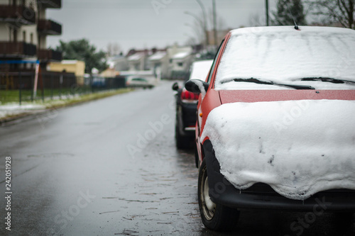 Red car covered with snow along the road. Concept of winter, snowfall