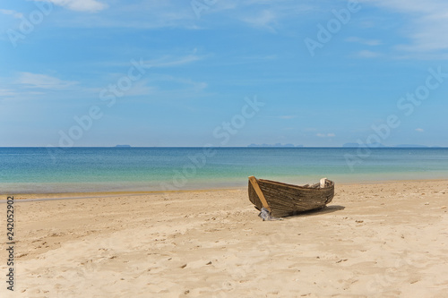 The old abandoned wooden fishing boat with fishnet on a sandy shore