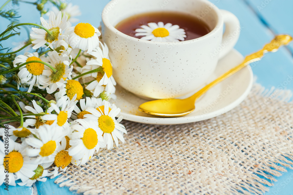 cup of herbal chamomile tea with fresh daisy flowers on wooden background 