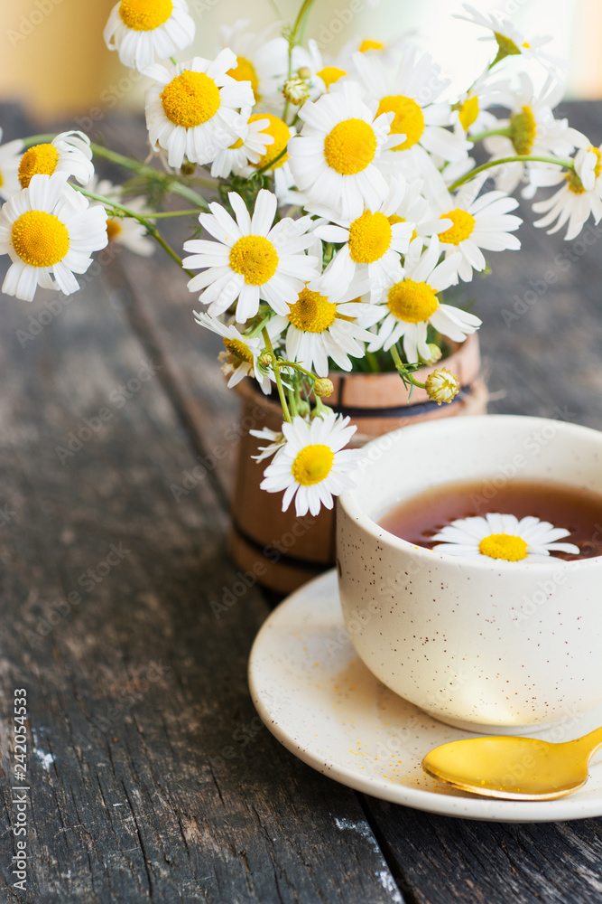 cup of herbal chamomile tea with fresh daisy flowers on wooden background 