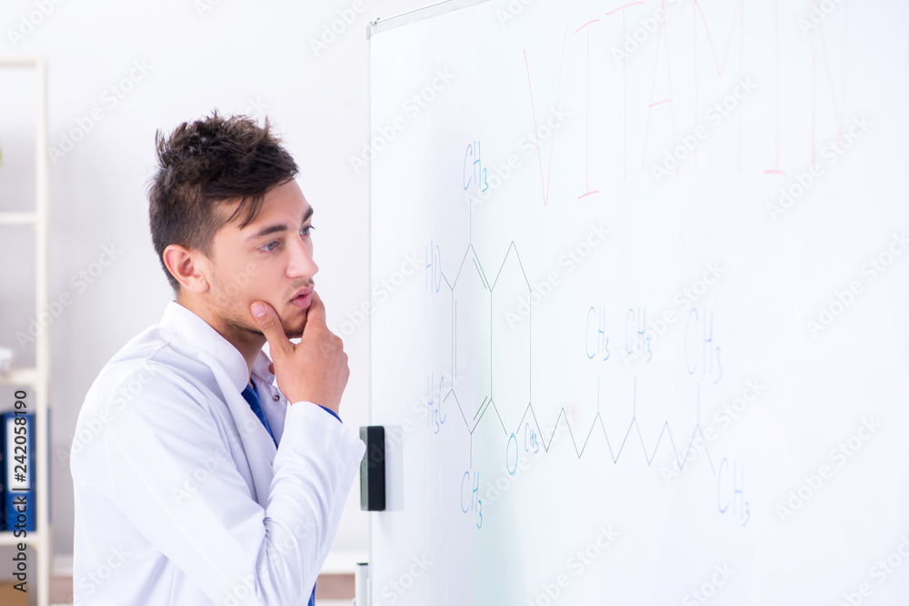 Young chemist standing in front of the whiteboard Young chemist standing in front of the whiteboard