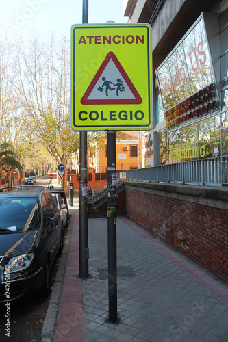 Spanish traffic signal, which indicates caution by the proximity of a school, having children nearby, the signal is fluorescent yellow, taken by day.