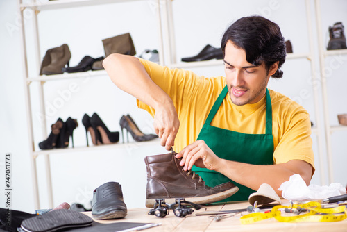 Young man repairing shoes in workshop 