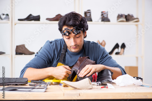 Young man repairing shoes in workshop 