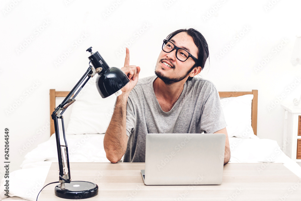 Happy man relaxing and using digital laptop computer on the bed at home.man checking social apps and working.wireless technology concept Happy man relaxing and using digital laptop computer on the bed at home.man checking social apps and working.wireless technology concept
