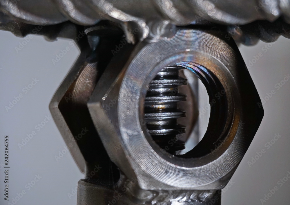 Nuts welded to a steel structure one after the another with a threaded steel rod between them Nuts welded to a steel structure one after the another with a threaded steel rod between them