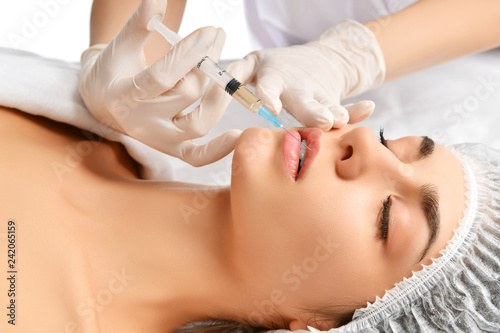 Plastic lips surgery beauty concept young brunette woman face and doctor hand in glove with syringe