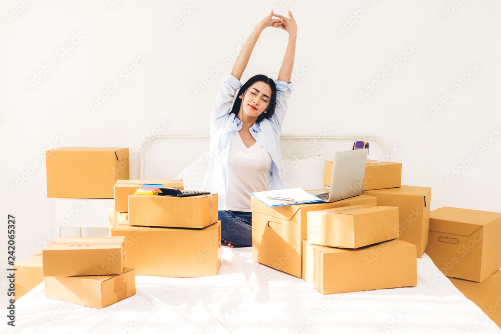 Young woman freelancer working and use laptop computer with cardboard box on bed at home - SME business online and delivery concept Young woman freelancer working and use laptop computer with cardboard box on bed at home - SME business online and delivery concept