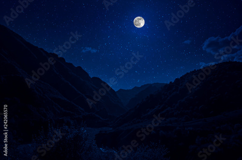 Mountain Road through the forest on a full moon night. Scenic night landscape of dark blue sky with moon. Azerbaijan