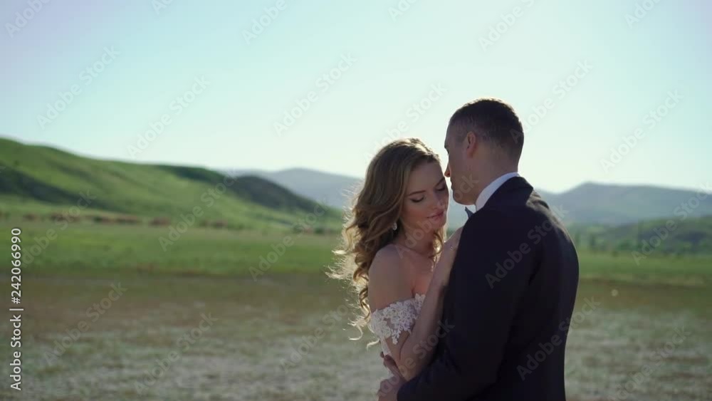Young beautiful bride in a wedding dress and groom hugging and kissing outdoors Young beautiful bride in a wedding dress and groom hugging and kissing outdoors