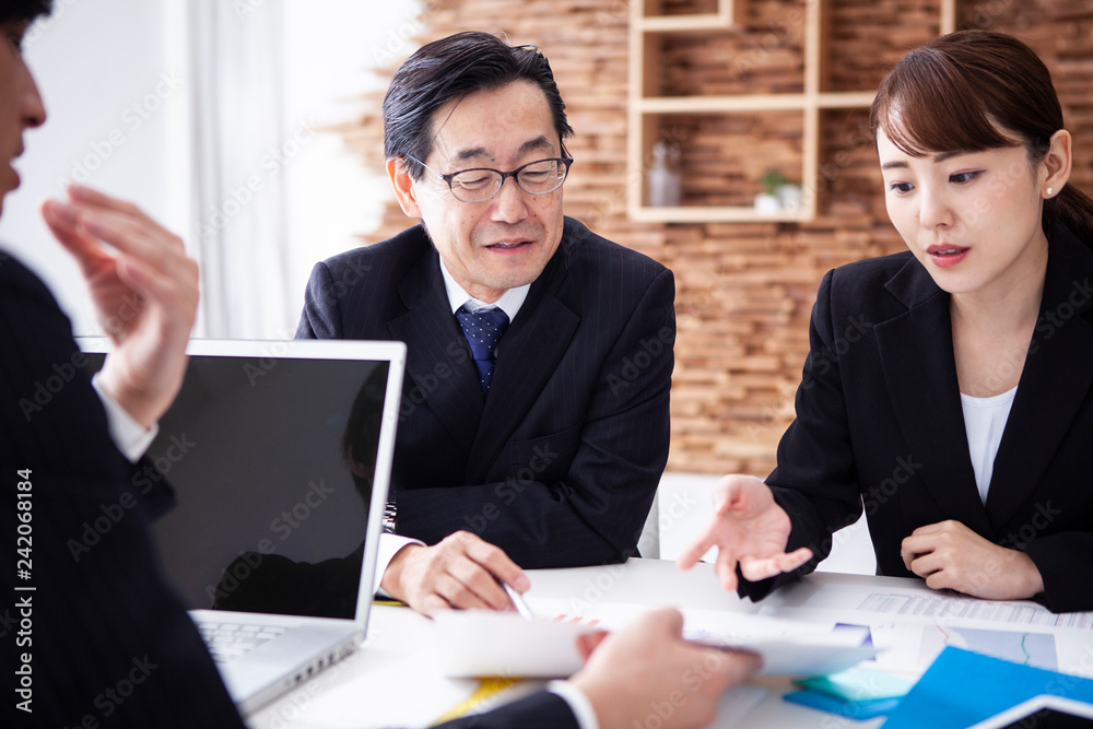 資料を見ながら真剣に意見を交わす会社員 資料を見ながら真剣に意見を交わす会社員