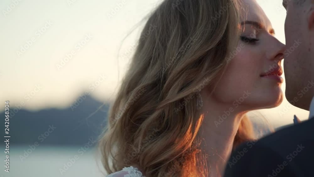 Bride and groom walking on mountain at sunset near sea Bride and groom walking on mountain at sunset near sea