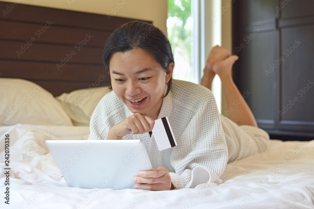 Woman shopping online and payment with laptop computer on bed at home Woman shopping online and payment with laptop computer on bed at home