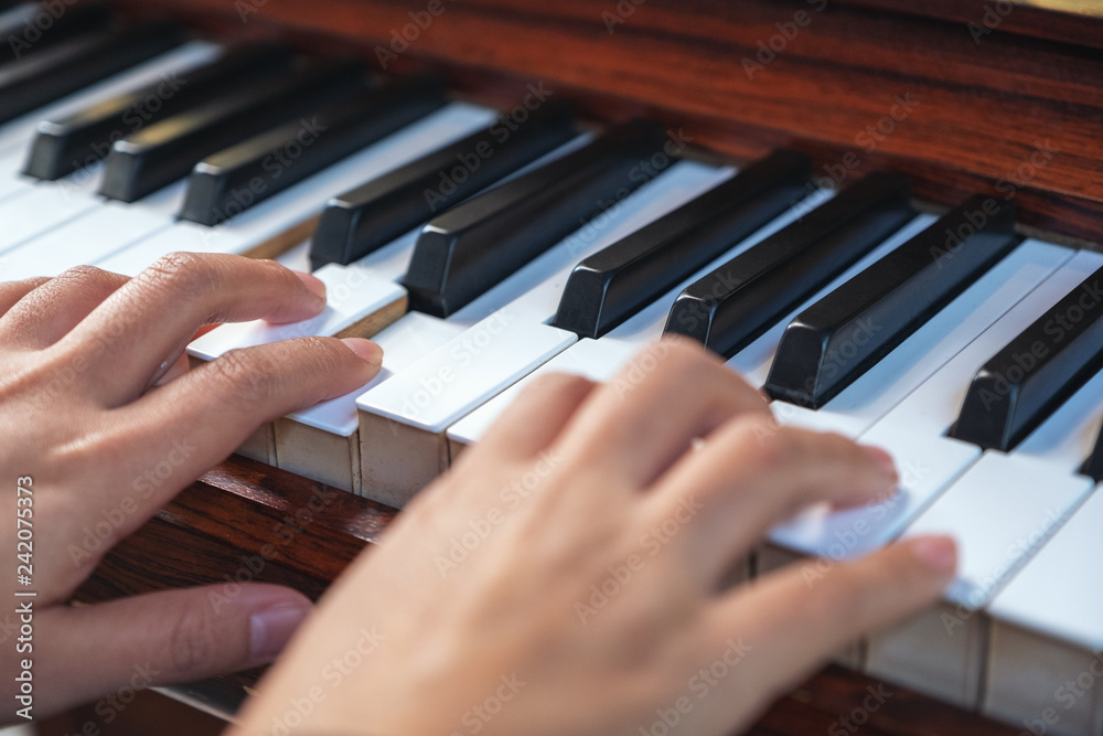 Fototapeta premium Closeup image of hands playing a vintage wooden grand piano