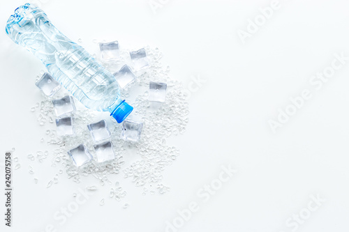 Bar desk with ice cubes and plastic bottle on white background top view space for text
