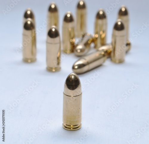 Thirteen gold full metal jacket 9mm bullets on a gray background
