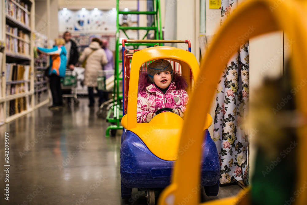 small children play in the children's cart while their parents choose the goods in the store