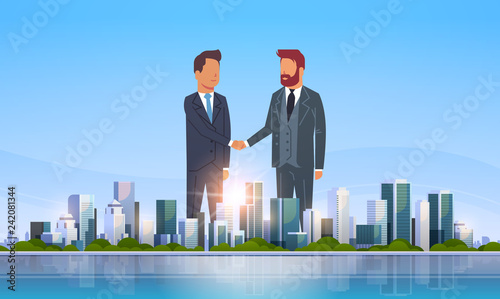 two businessmen shaking hands partners successful agreement business deal hand shake concept over big modern city building skyscraper cityscape skyline flat horizontal