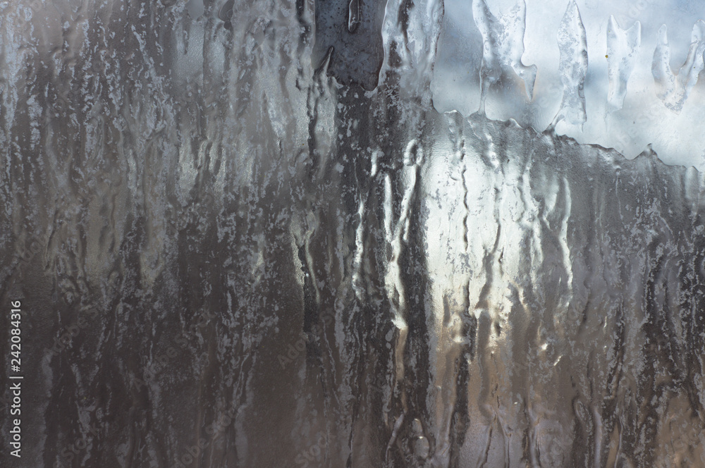 Fototapeta premium Frozen ice on glass window. Gray background