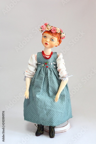 doll-girl in a dress standing on his head a wreath.