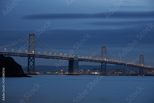 The San Francisco - Oakland Bay Bridge with San Francisco in the background during evening blue hour.