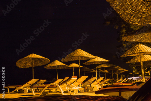 Fototapeta Naklejka Na Ścianę i Meble -  Empty sunbeds with umbrellas at night. Close up concept