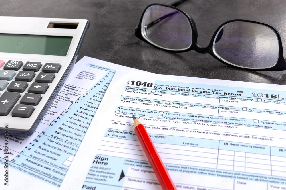 United States federal income tax return IRS 1040 documents, with pencil, calculator and eyeglasses United States federal income tax return IRS 1040 documents, with pencil, calculator and eyeglasses