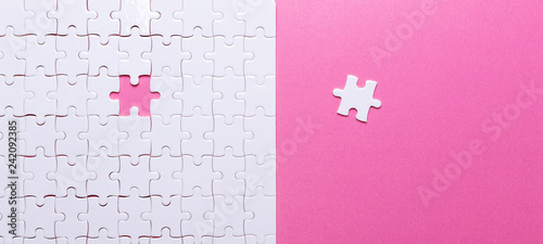 White puzzle on pink background. Missing piece. Top view photo