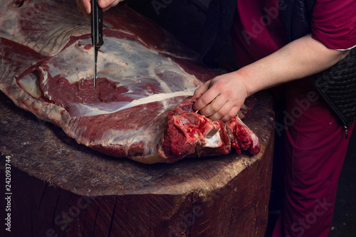 a butcher cuts a large carcass of meat
