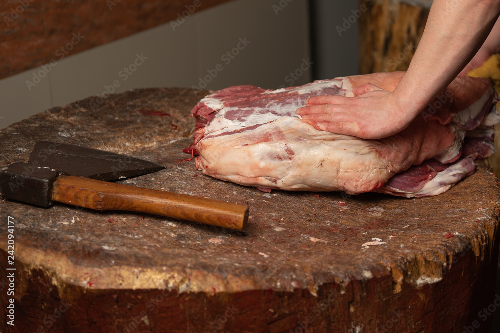 The butcher runs the butcher's knife to cut the lamb.