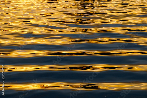 Parallel lines of water wave with sunlight refection at sunset