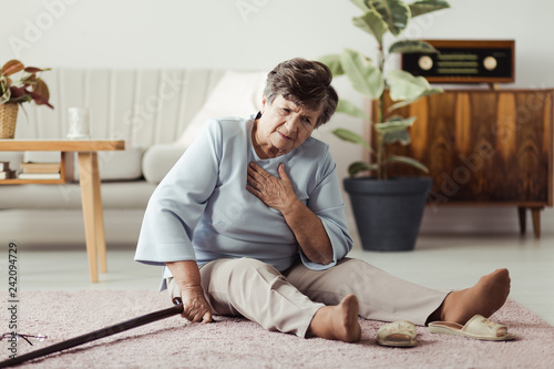 Weak senior woman with breathlessness sitting on the floor with walking stick