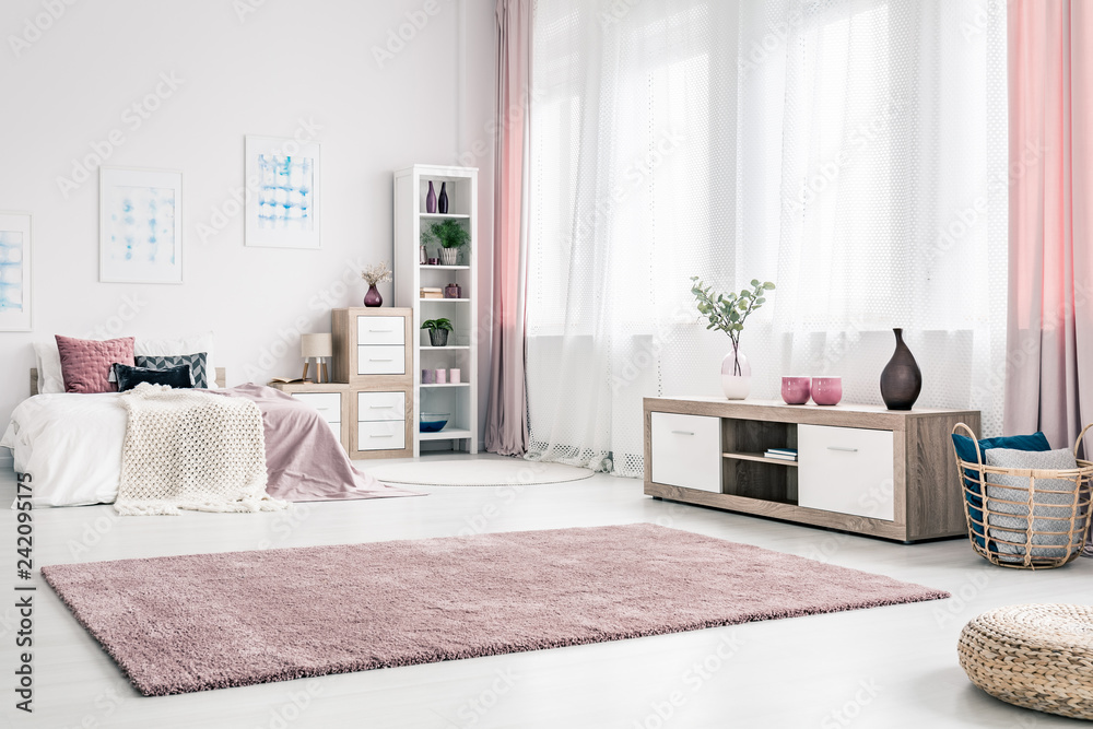 Big fluffy rug on white wall of classy bedroom interior with wooden cabinet and wicker basket - obrazy, fototapety, plakaty 