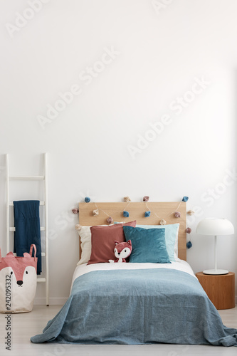 Singe bed in bright bedroom interior with copy space on empty white wall