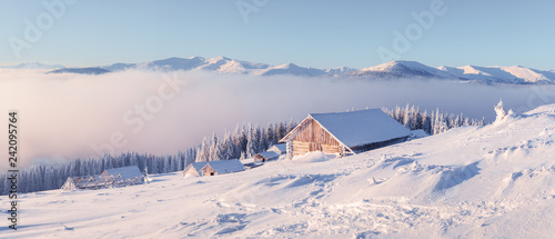 Fantastic winter landscape with wooden house in snowy mountains. Christmas holiday concept