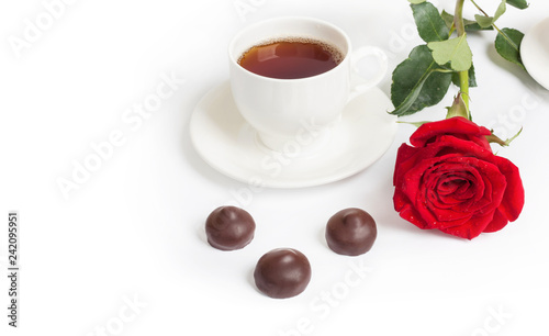 Beautiful red rose and cup of hot tea with chocolate