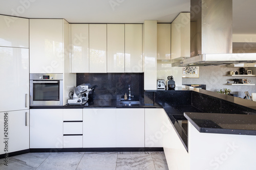 White kitchen with black marble top and large hood