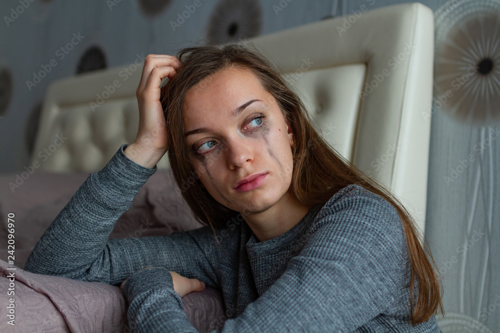 Depressed, sad, lonely woman sitting near the bed and crying because of problems at work and troubles in relationships. Domestic, woman violence. Life problems Depressed, sad, lonely woman sitting near the bed and crying because of problems at work and troubles in relationships. Domestic, woman violence. Life problems