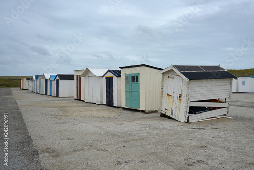 Row of multiple old discarded and damaged beach sheds on the beach of island Texel in the Netherlands